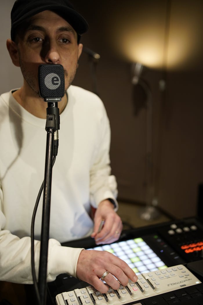 A musician working with studio equipment, including a microphone and sound mixer.