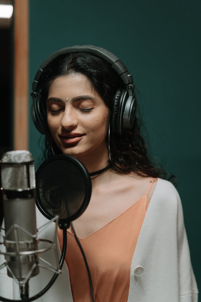 Portrait of a female singer recording vocals in a professional music studio.